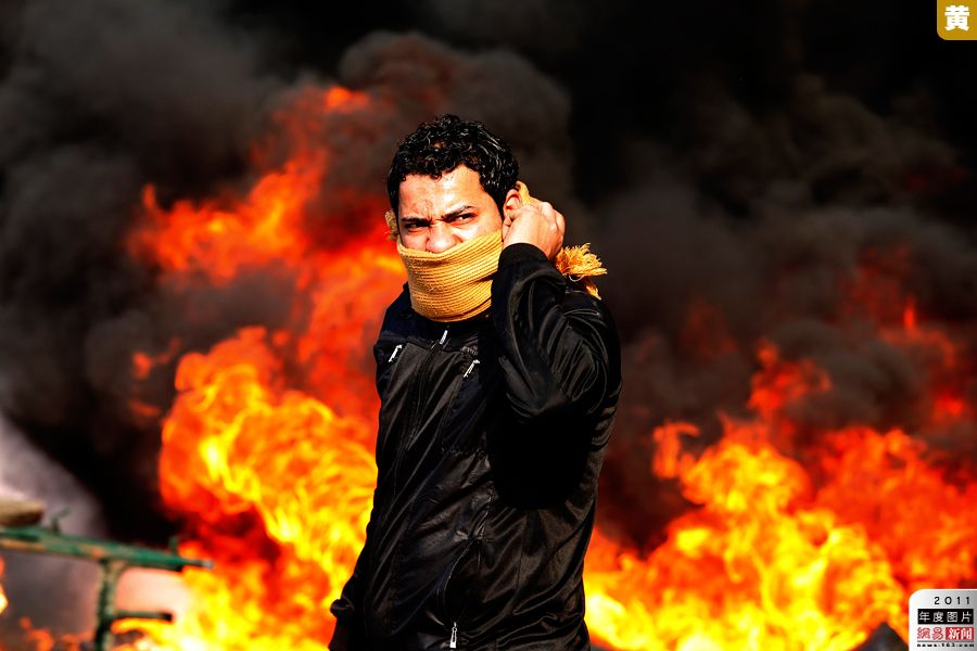 2011年1月28日，埃及首都开罗，一名抗议者站在燃烧的路障前。“抗议者”当选为美国《.jpg